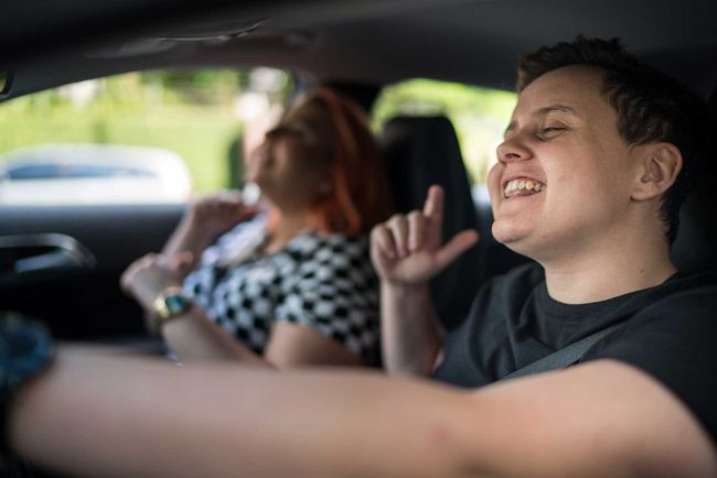 LGBTQのカップルが車の中で聞いて、歌って、踊って