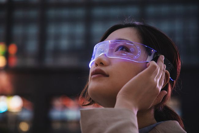 жінка за допомогою смарт-окулярів перед офісною будівлею