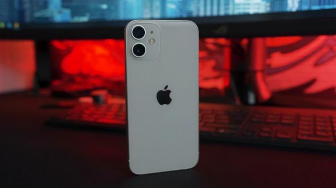 Apple iPhone 12 mini върху маса с червен и син фон.