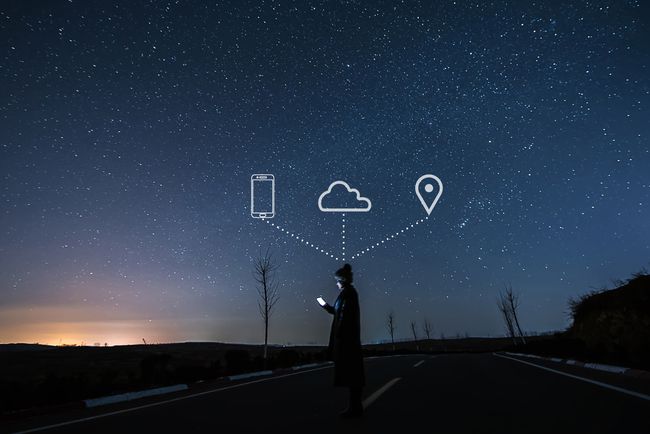 星空にスマートフォン、雲、地図のアイコンが表示されているスマートフォンを使用している人。