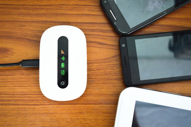 Un enrutador Wi-Fi con antenas internas cerca de teléfonos y tabletas