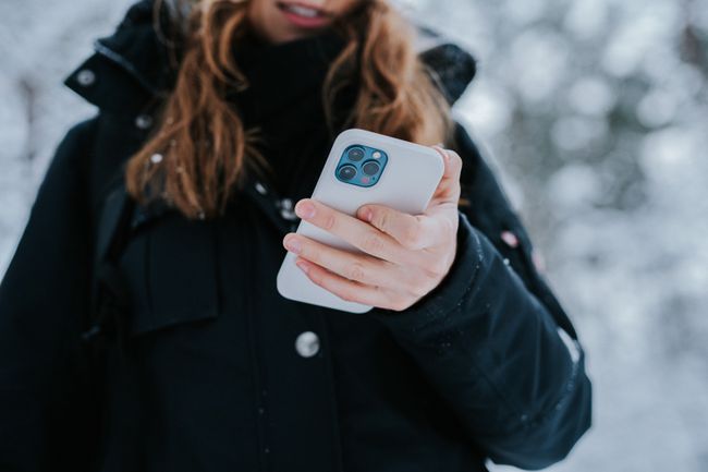 En person udendørs, om vinteren, der holder en iPhone 12.