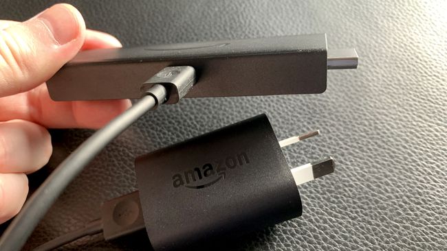 Amazon Fire Stick a hozzá csatlakoztatott töltőkábellel.