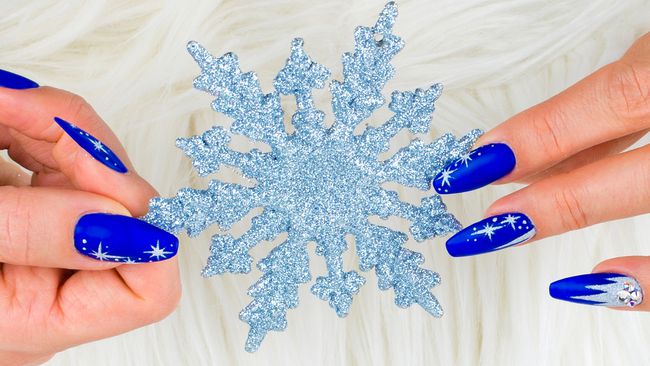 Una mujer con uñas azules sosteniendo un copo de nieve que parece una Elsa de acción en vivo de Frozen.