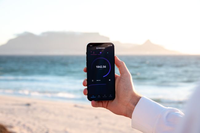 Ruka drži telefon s testom brzine na ekranu, plaža u pozadini