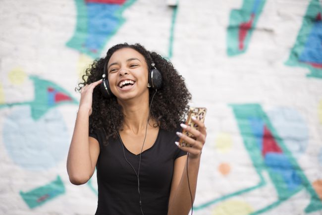 Adolescente ouvindo mp3 player contra a parede com grafite