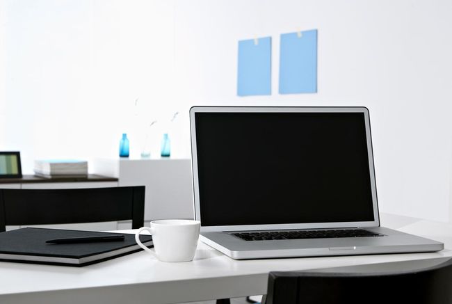 커피 머그와 책이 있는 탁자 위의 MacBook Pro