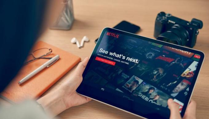 タブレットで Netflix を見ている人。 