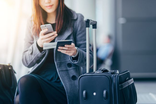 Ženska na letališču drži pametni telefon in potni list