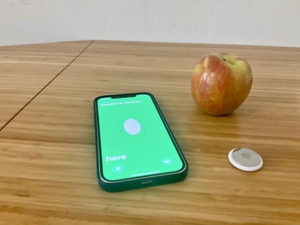 サイズ比較のためにiPhoneとAppleの隣にペアリングされたAppleAirTag