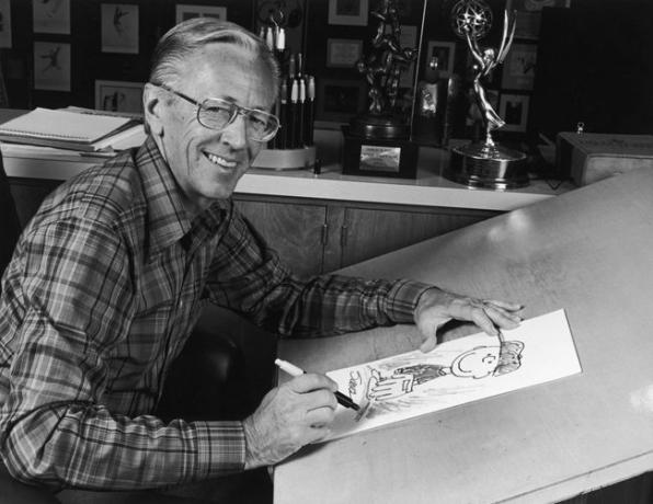 1978: Porträtt av den amerikanske serietecknaren Charles M Schulz (1922 - 2001), skaparen av serieserien " Peanuts", sitter vid sitt ritbord i studion med en bild på sin karaktär Charlie Brown och några priser bakom honom. Schulz skapade serieserien 1950. 