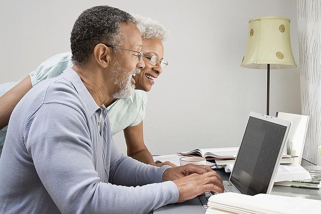 Pareja en su oficina en casa mirando una computadora portátil.