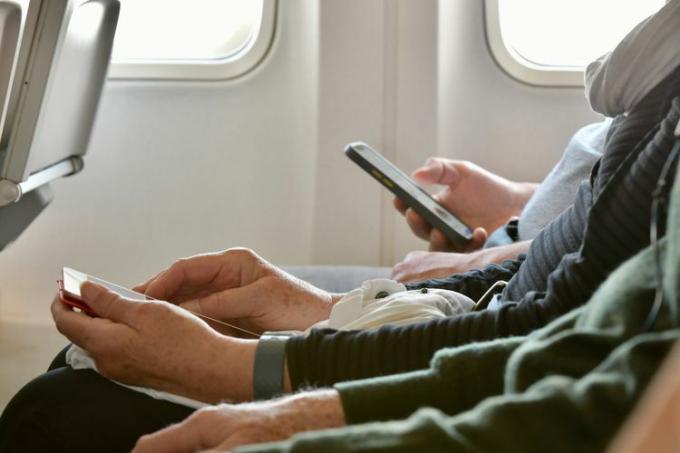 Pessoas usando dispositivos eletrônicos em um avião.