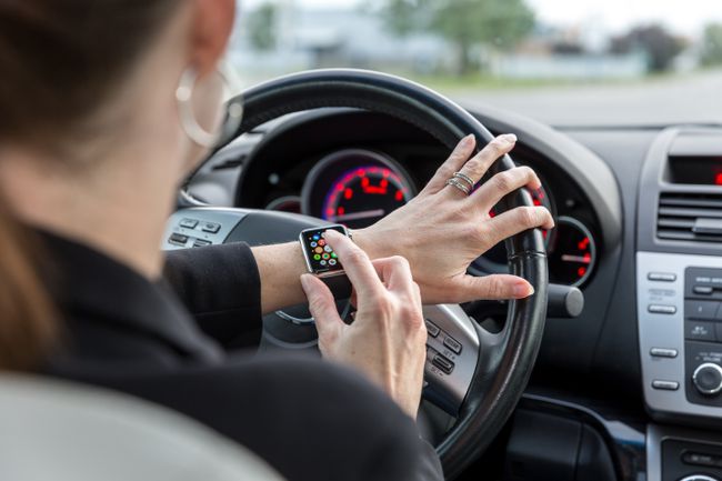 Moteris, dėvi „Apple Watch“, vairuodama automobilį