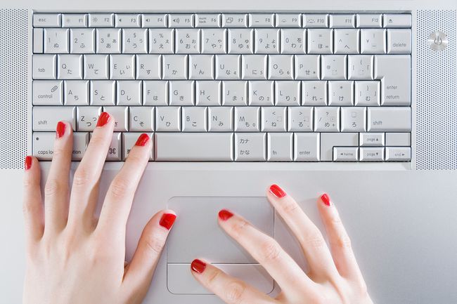 Mujer, llevando, rojo, esmalte de uñas, usar la computadora portátil, primer plano, de, manos, vista de arriba