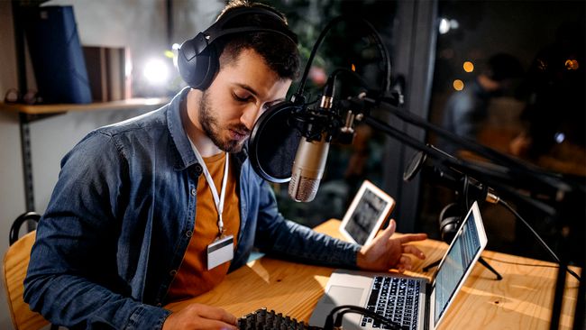 Un homme enregistre un podcast avec un microphone et un ordinateur portable.