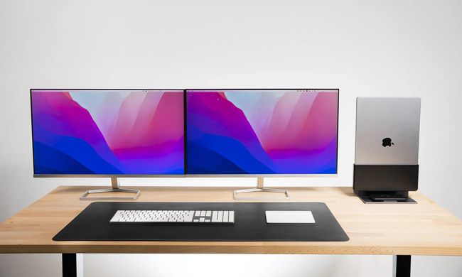 Thunderbolt 4 ProDock にドッキングされた MacBook と、2 台のコンピューター モニター、机の上にある外付けキーボードとトラックパッド。