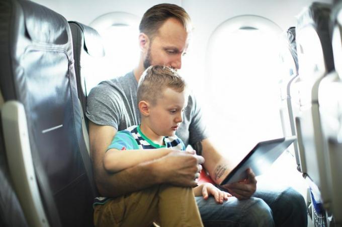 Pai e filho usando um tablet em um avião.