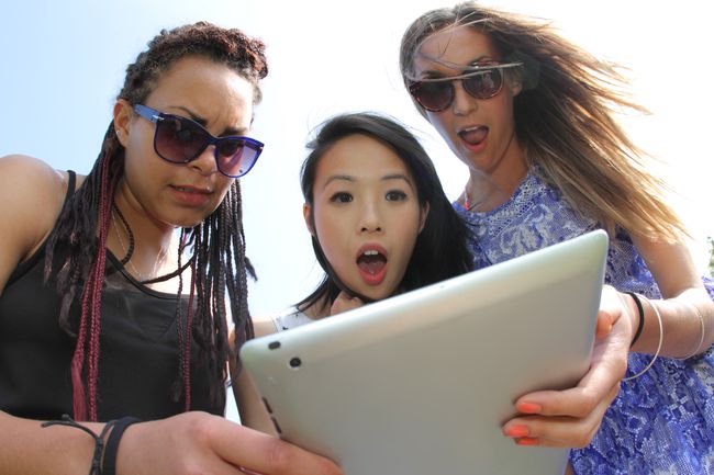 Un grup de prieteni ținând în mână o tabletă iPad