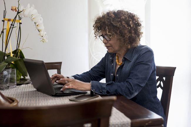 En person, der skriver på en bærbar computer ved køkkenbordet i deres hjem.