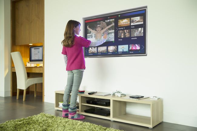 Dievča používa dotykovú obrazovku televízie v obývacej izbe