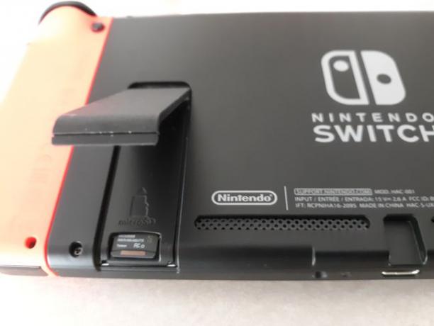 Com o Nintendo Switch desligado, insira o cartão microSD na parte de trás do sistema.