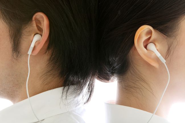 Zbliżenie na dwie osoby prawidłowo noszące przewodowe słuchawki douszne.