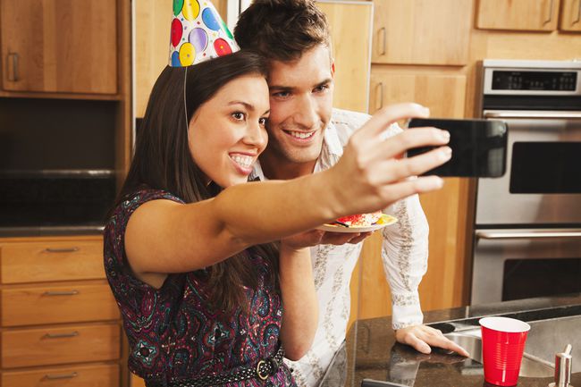 Et bilde av en mann og en kvinne som poserer for en selfie på en bursdagsfest.