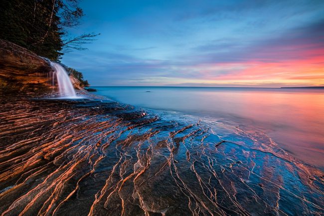 Una pequeña cascada en una playa al atardecer en este fondo de pantalla de océano gratis