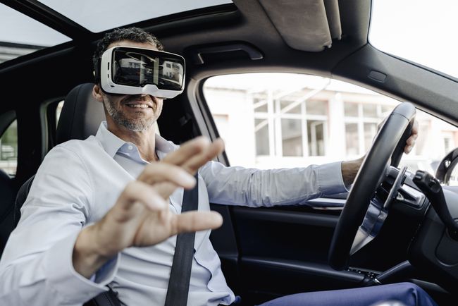 Verslininkas, nešiojantis VR akinius, vairuojantis automobilį